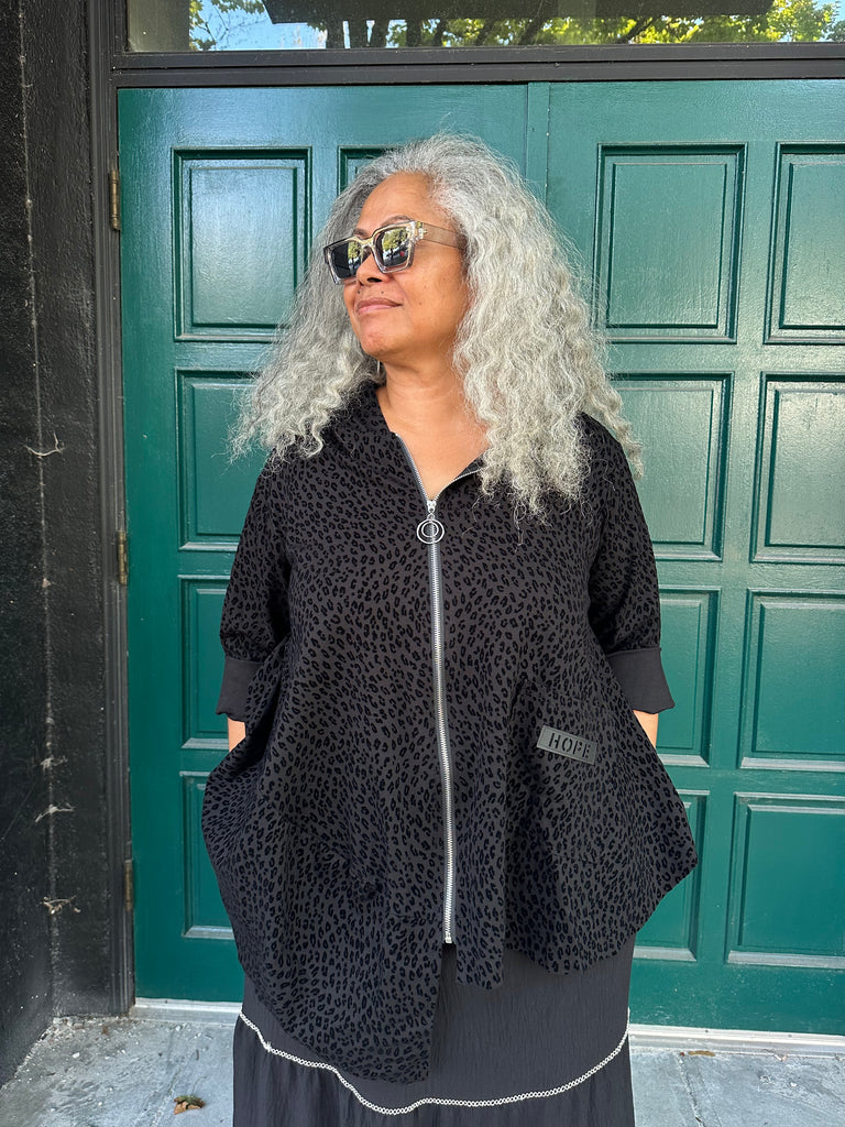 Person wearing a black textured hoodie in front of a green door