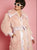 Person wearing a fluffy pink coat with a sequin belt against a pink background