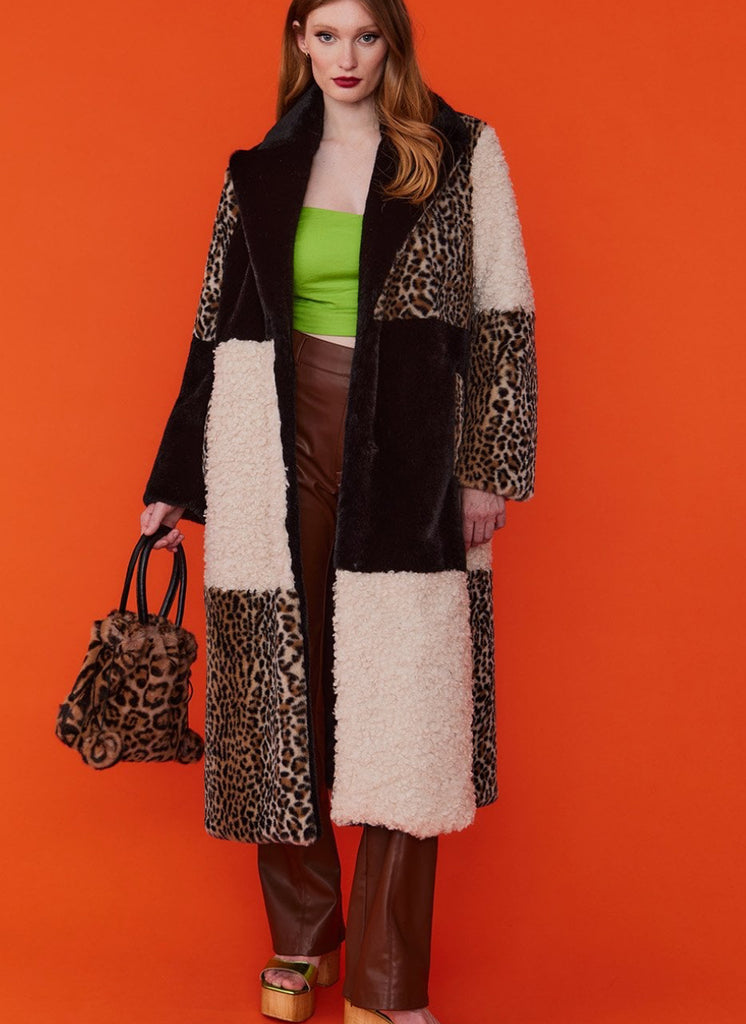 Woman wearing a patchwork coat with leopard print and brown elements on an orange background