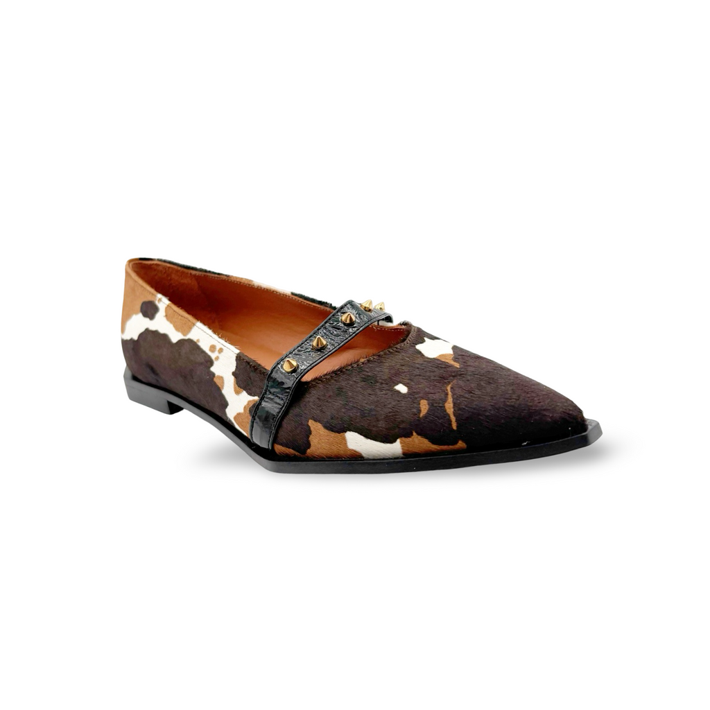 Brown and white cow print flat shoe with black accents on a white background