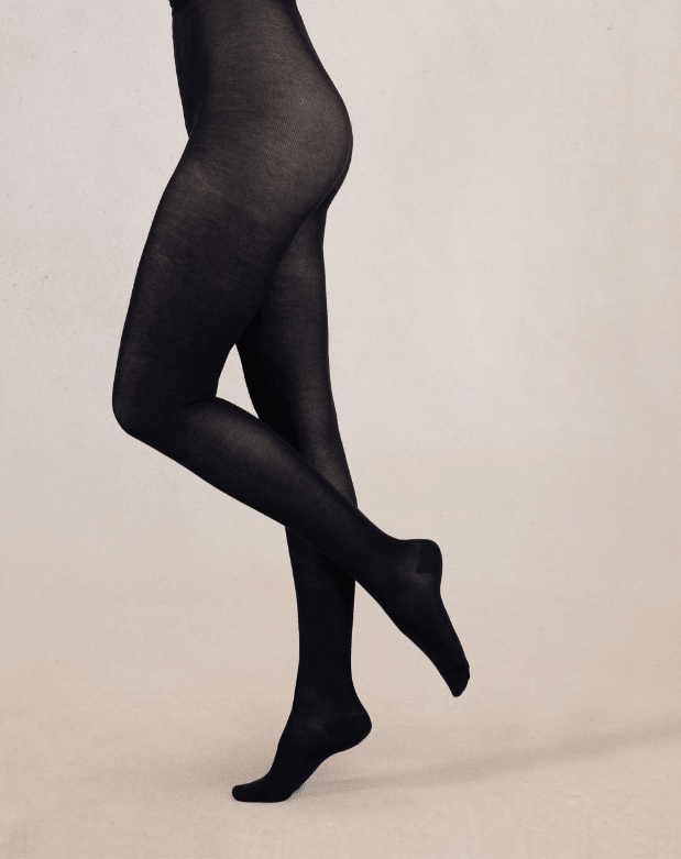 Black tights worn by a person on a beige background